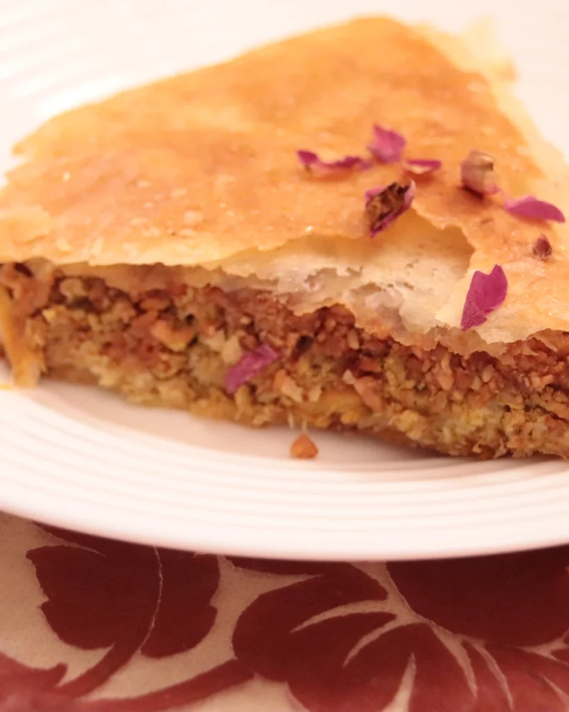 Pastilla au poulet et aux amandes Part de pastilla au poulet et aux amandes décorée de pétales de rose, plat sucré-salé d'origine andalouse